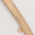 The scabbard of the saber is covered with gold and carved ornament made by the method of engraving on the metal surface.